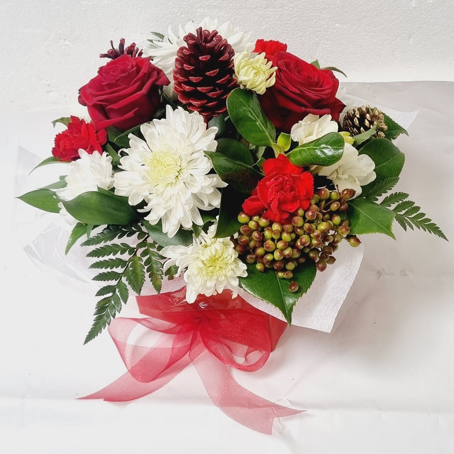 A white posybox of red and white flowers and Christmas decorations