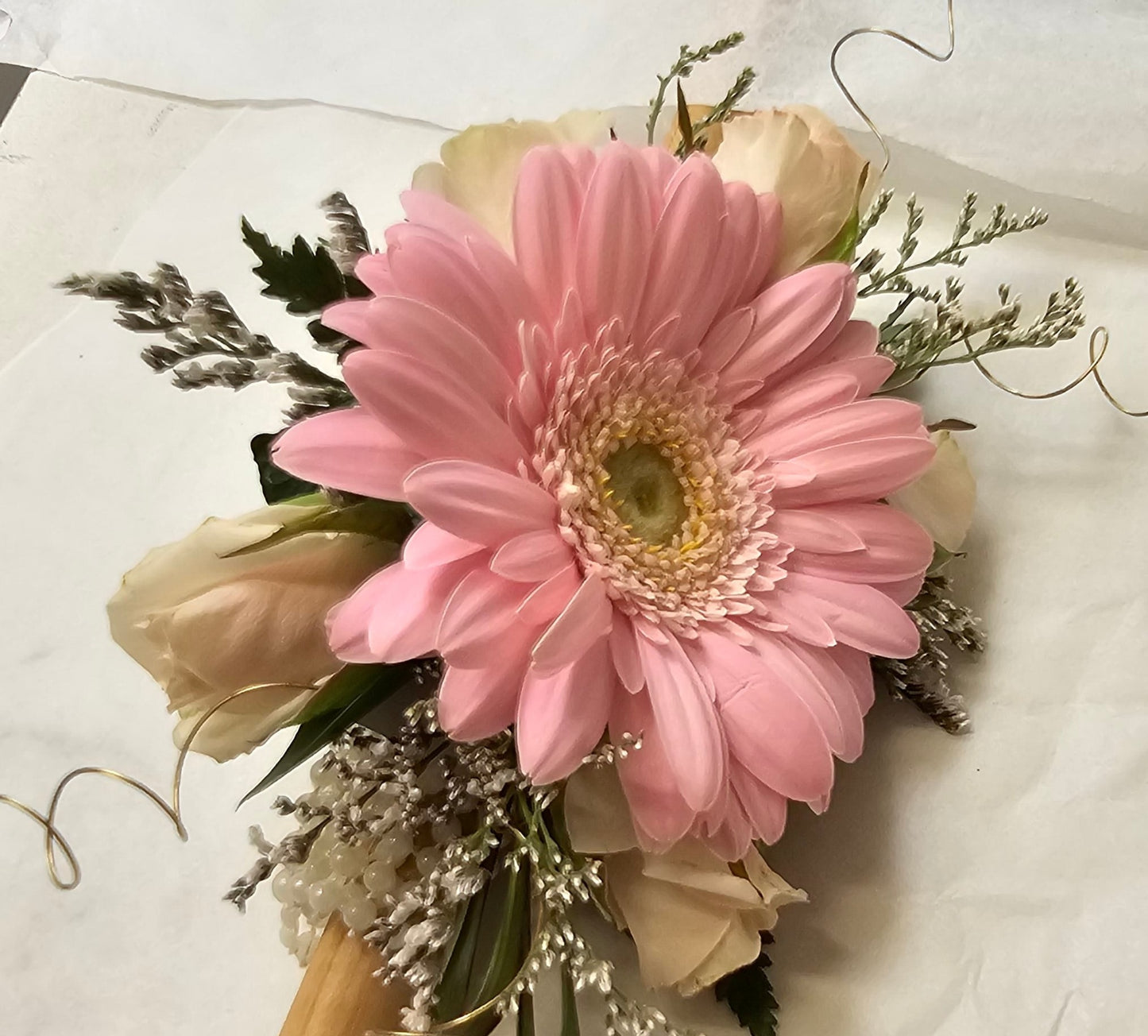 Pink gerbera, pink rose buds and foliage wrist corsage