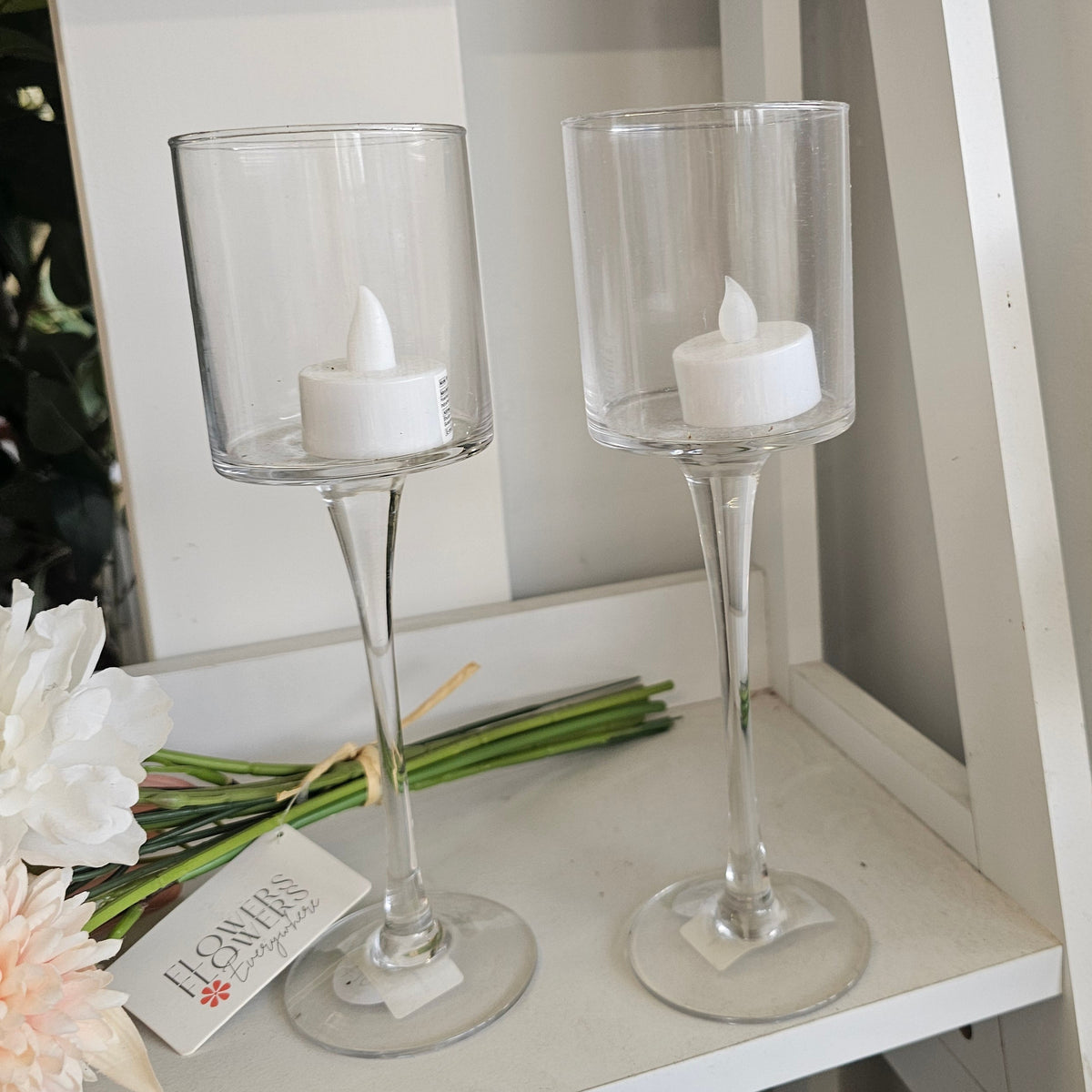 Two clear glass candlestick holders with white tea light candles