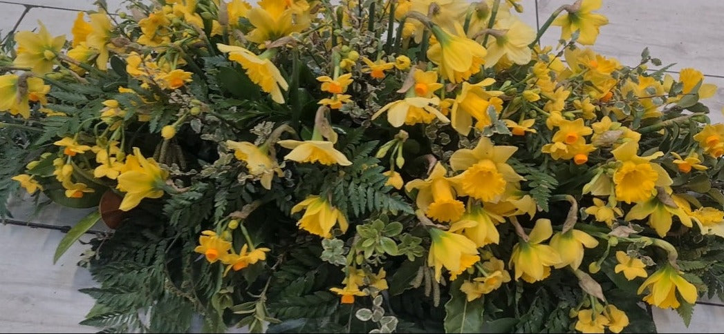 Casket spray made with a variety of daffodils and joquils