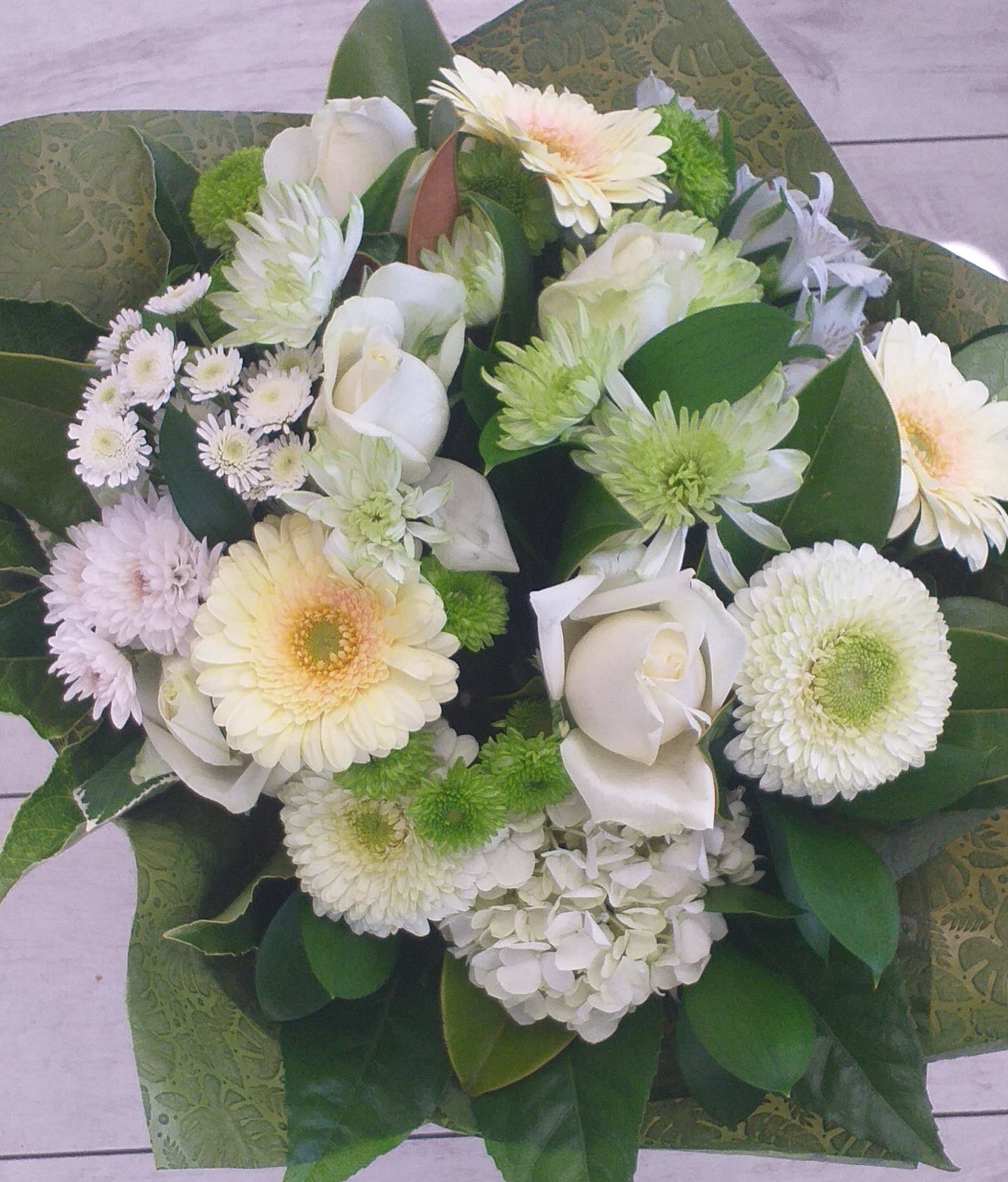 bouquet of cream and green flowers, gerbera, roses, chrysies, and alstro wrapped in green fabric