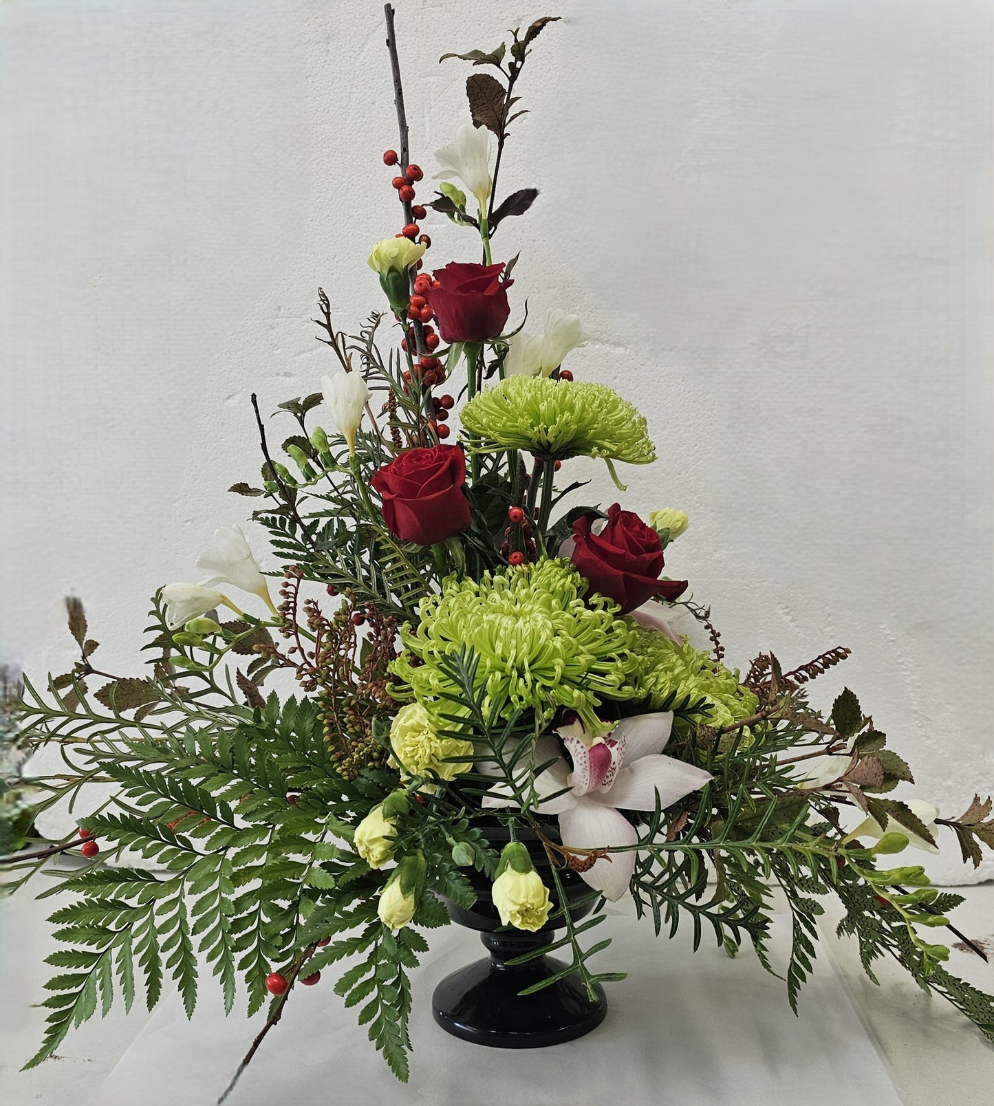 Floral arrangement with red roses, green chrysanthemums, and white orchids with fern