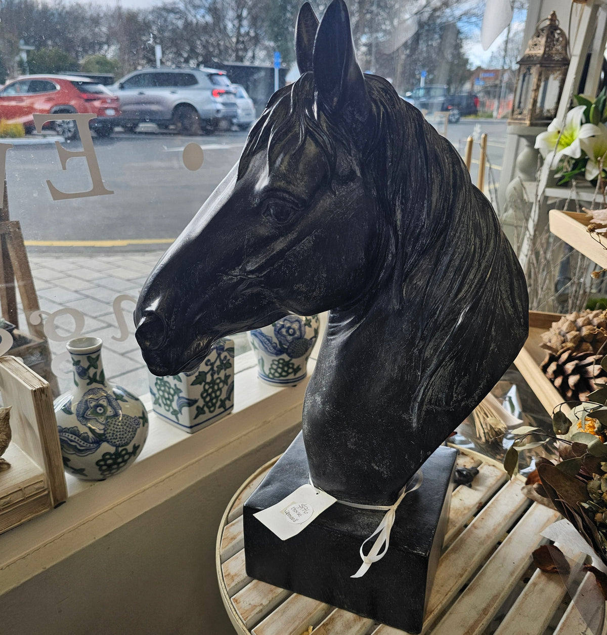A black horse head bust sculpture displayed on a black base
