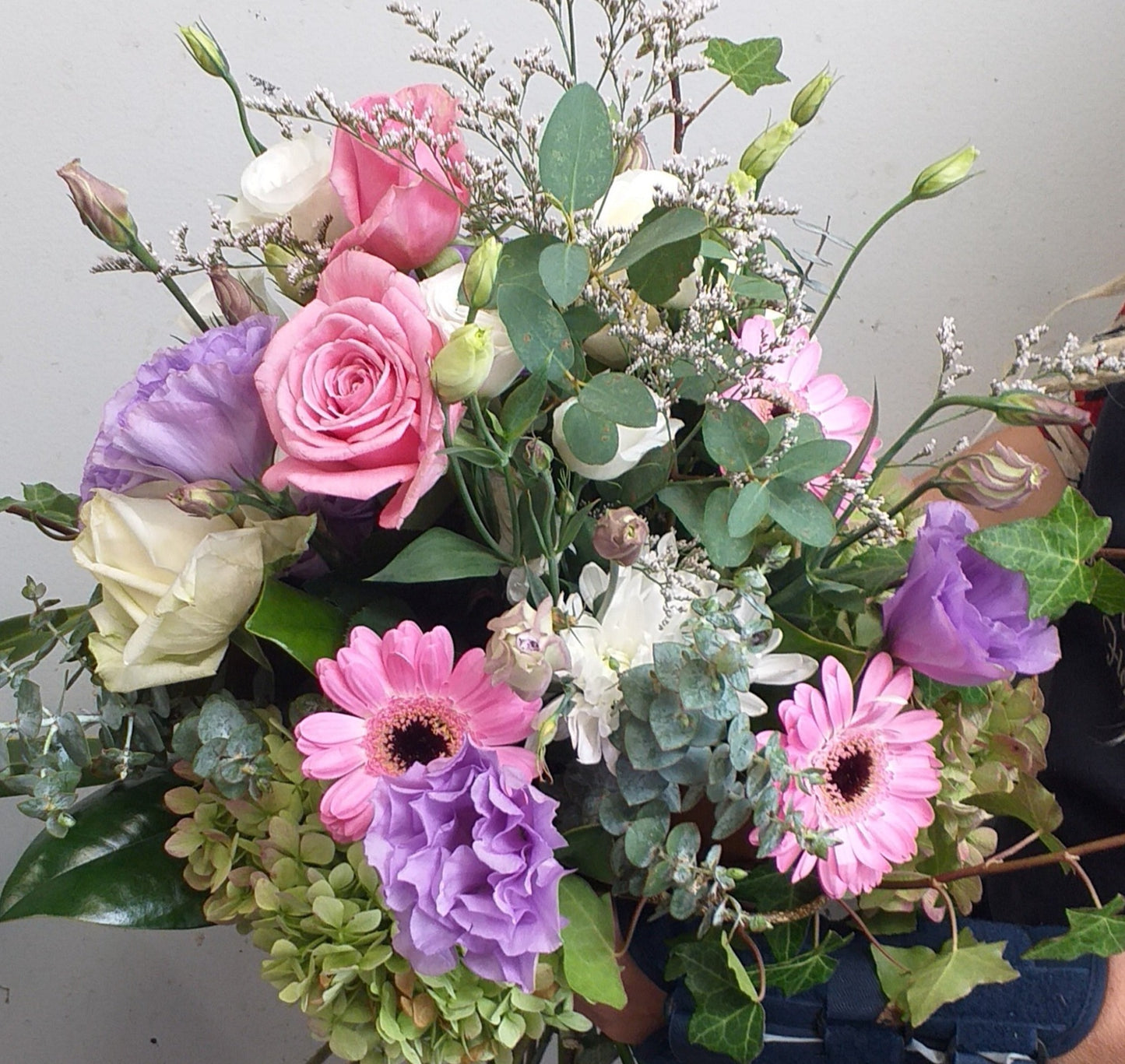 whimsical bouquet with roses, gerberas, gum, lisianthus, ivy and limonium,