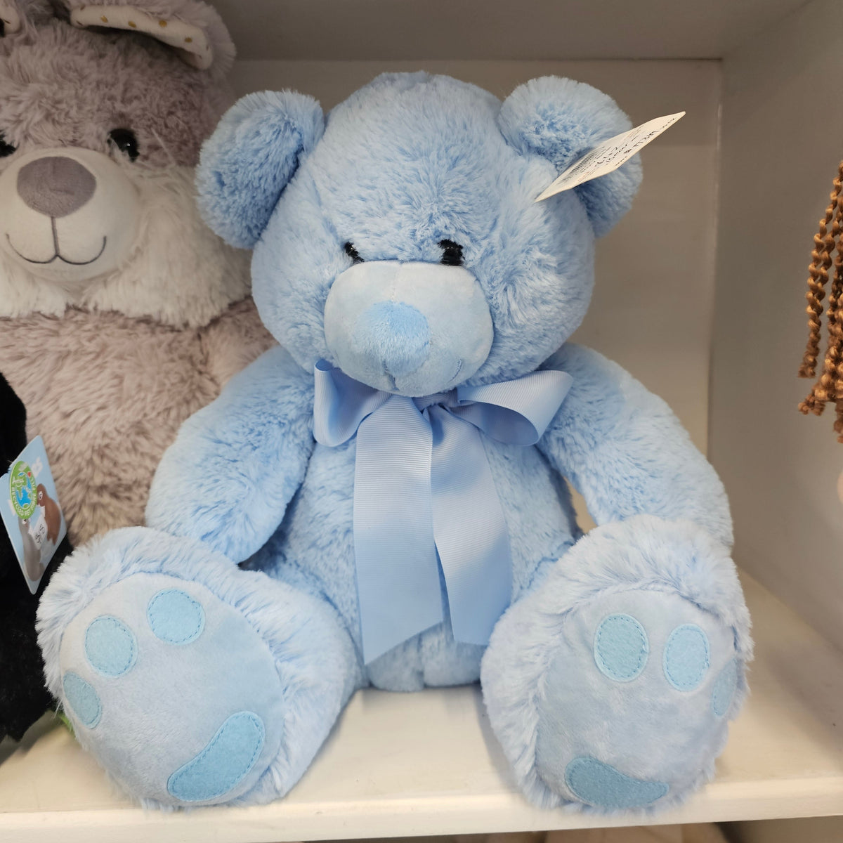 A light blue plush teddy bear with a matching blue satin bow and light blue paw pads