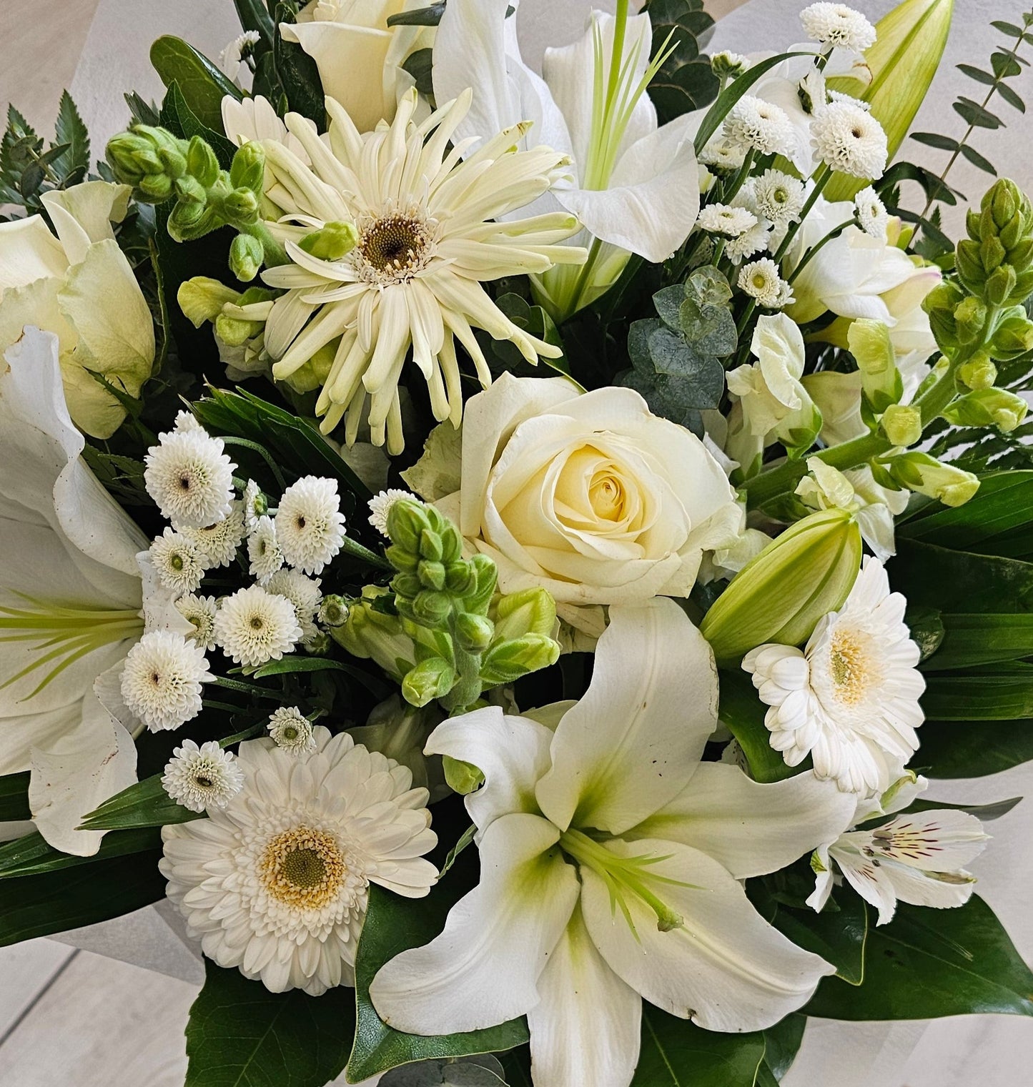 white flowers, roses, lilies, stock, chrysies, gerbera, large leaves greenery including gum