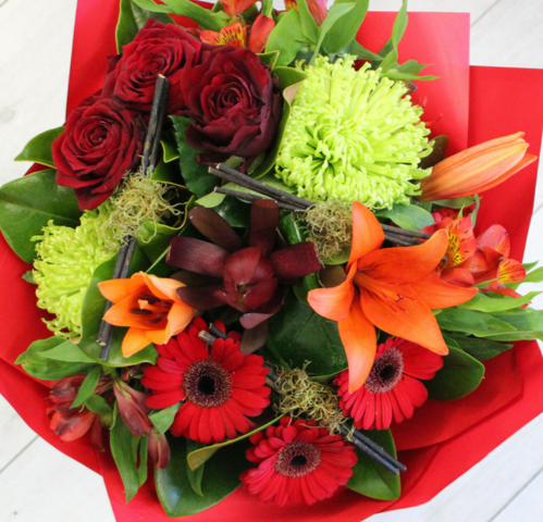 Heart Warmer flower bouquet, orange lily, green chrysanthemum, red leucadendron, gerberas, alstromeria wrapped in red