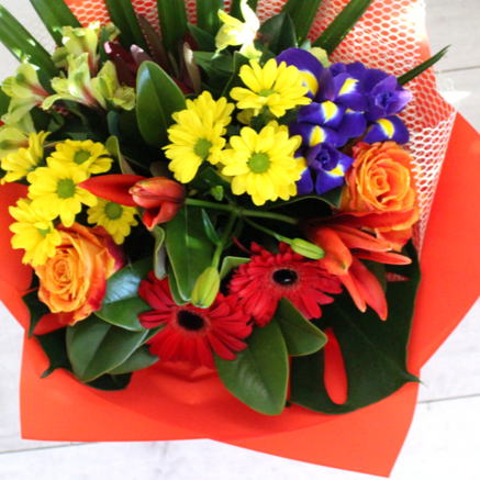 Bright and Bold bouquet, orange and pink roses, yellow chrysanthemums, blue and yellow iris, red gerberas, yellow alstroemeria, yellow palm, astatic lily. Wrapped in red and white.