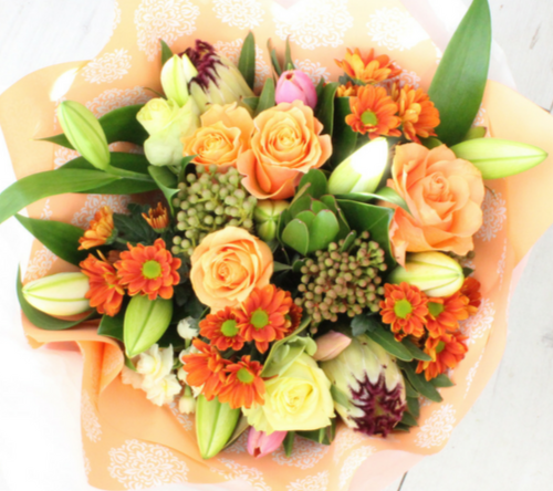 Apricot/peach coloured flowers, roses, protea, lilies, berries, chrysies