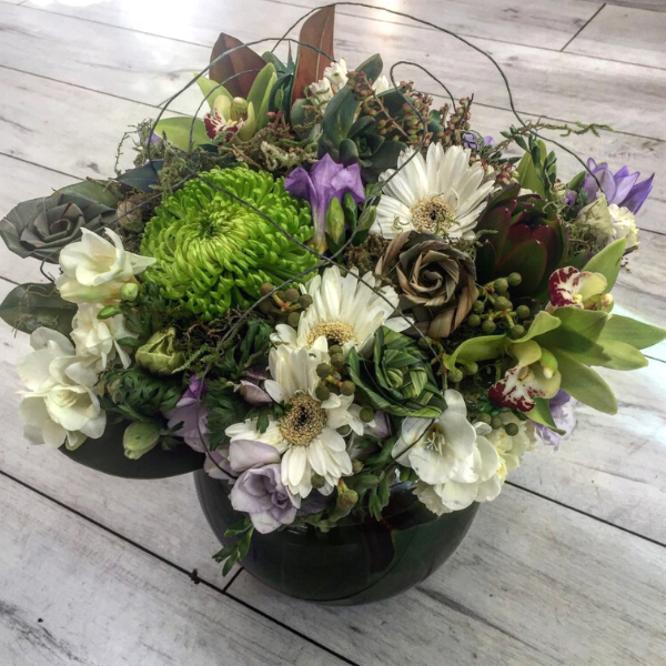 bouquet is made with interesting plant material to give a textured look. included are flax flowers, freesia, gerbera, pieris, orchids (when available), ice plant, molenbeckia, spray chrysies and moss