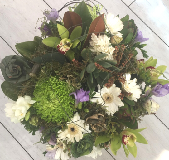 bouquet is made with interesting plant material to give a textured look. included are flax flowers, freesia, gerbera, pieris, orchids (when available), ice plant, molenbeckia, spray chrysies and moss