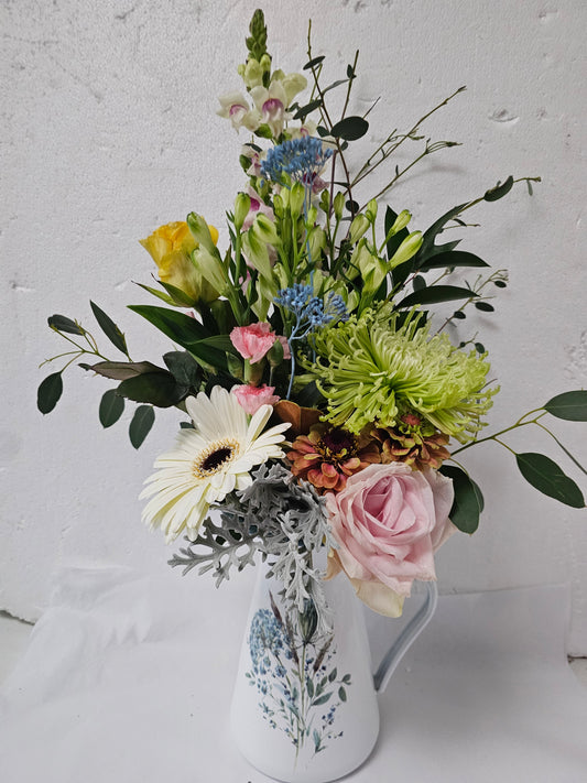 A blue floral jug flower arrangement