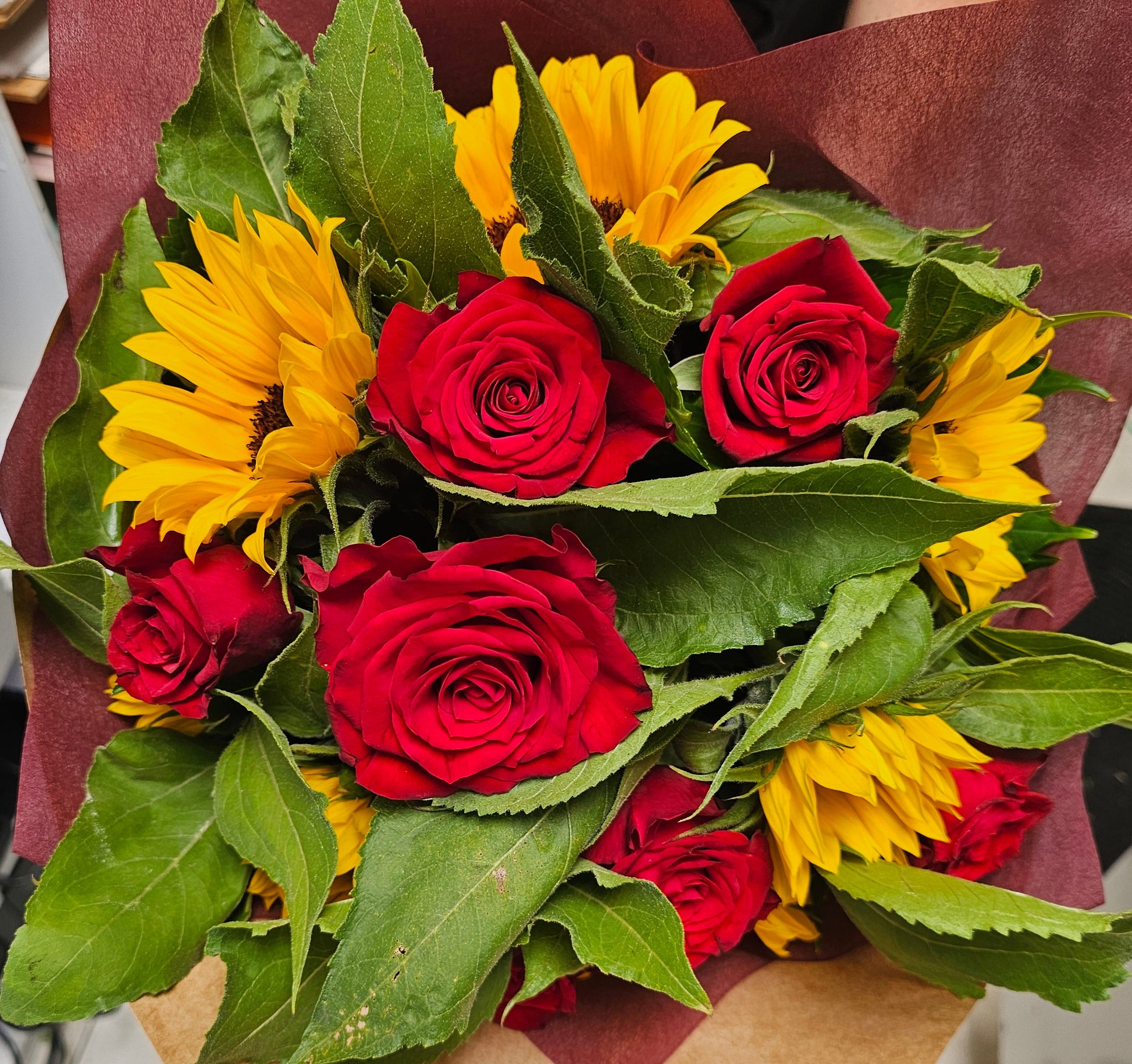 bouquet of roses and sunflowers in a red wrap
