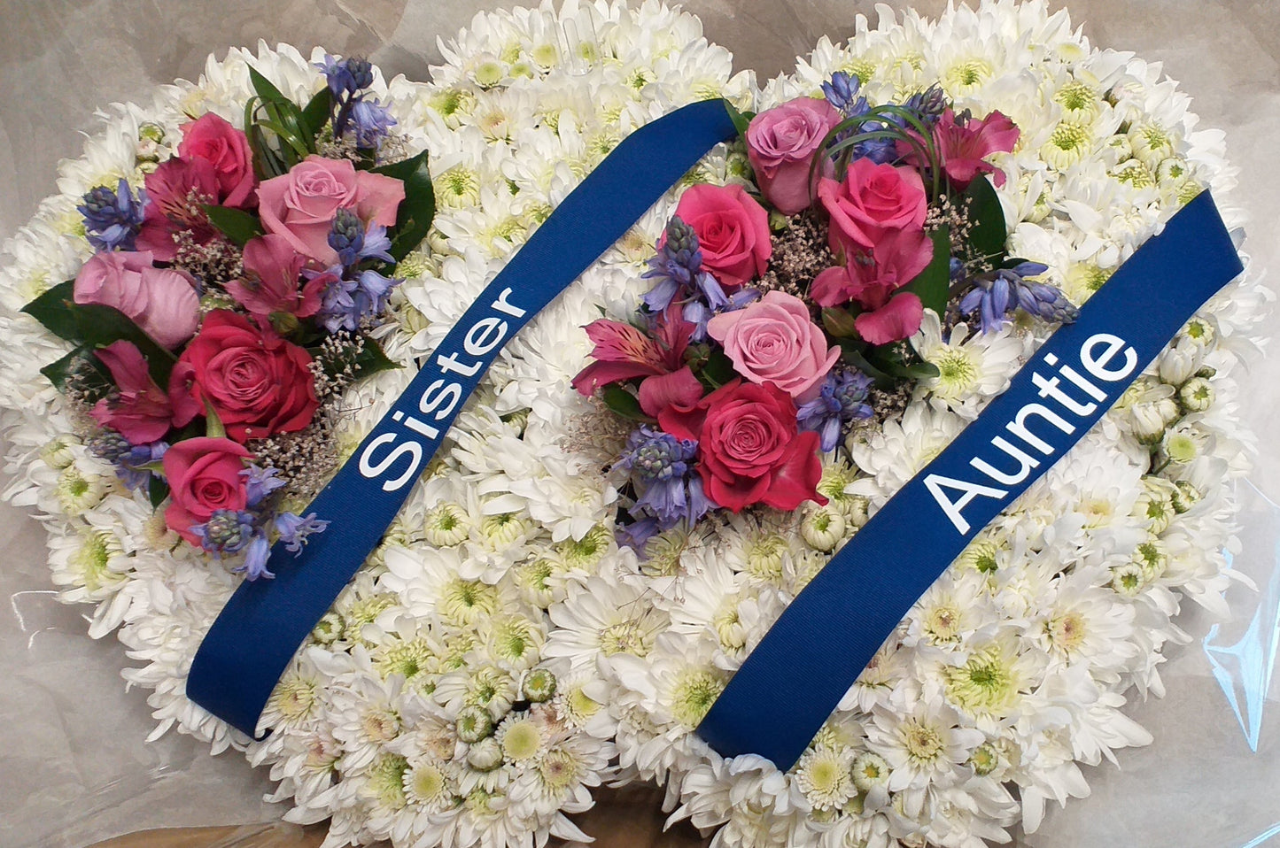 Casket pillow double heart, made with white chrysanthemums, pink roses and blue bells