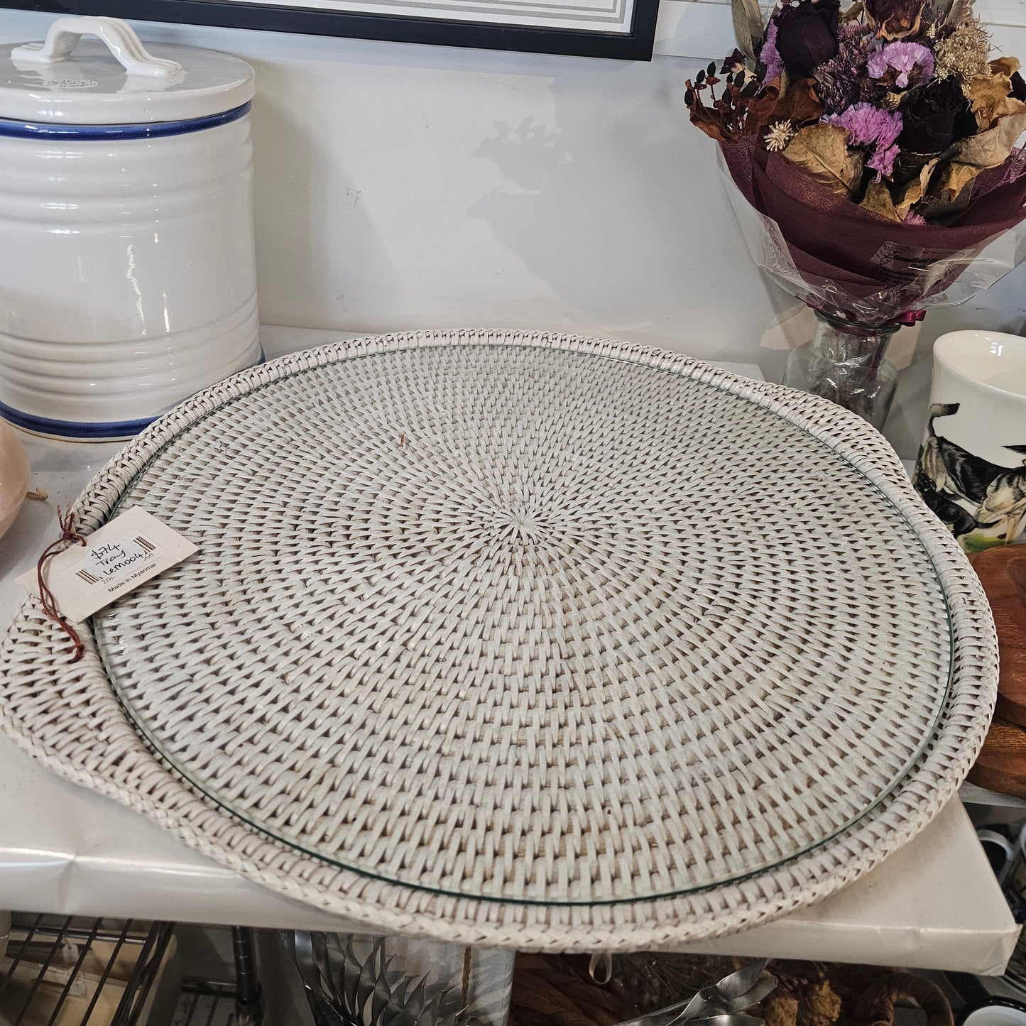 A glass tray with a round woven beige placemat with a concentric spiral pattern