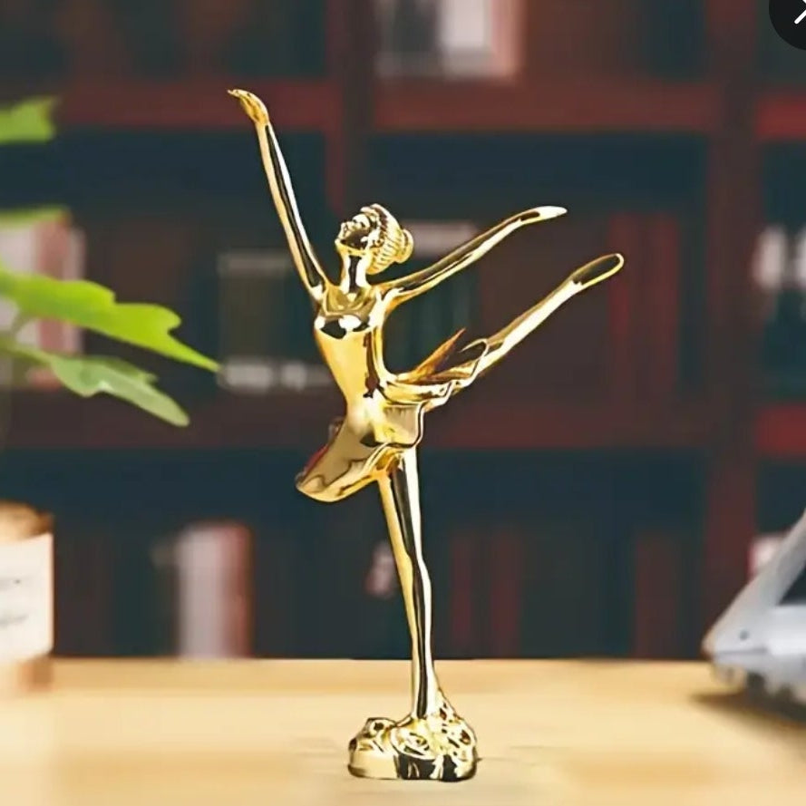 Gold ballet dancer statue on a wooden surface