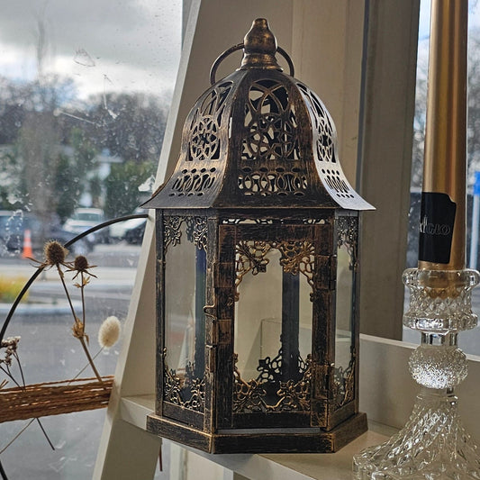 A decorative black metal lantern with gold detailing 