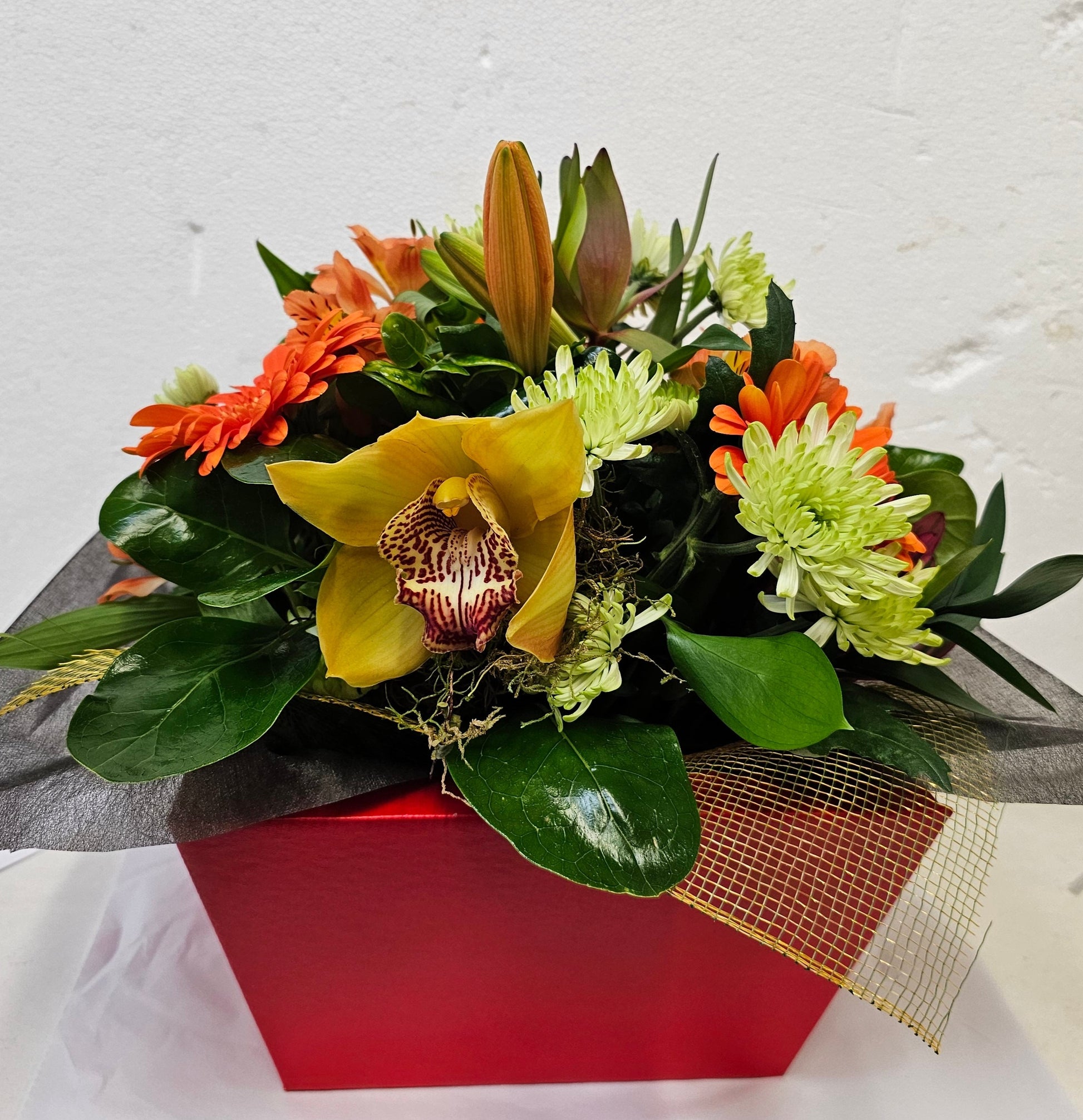 arrangement in a box includes, lilies, gerbera, spray chrysies, orchid