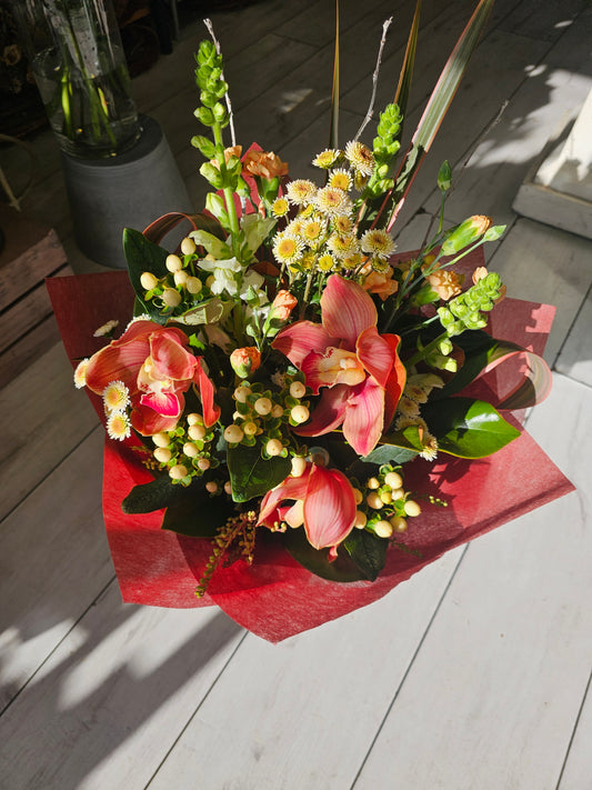 red cymbidium orchid with cream berries, mini white chrysies, and antirrinums wrapped in red vylene