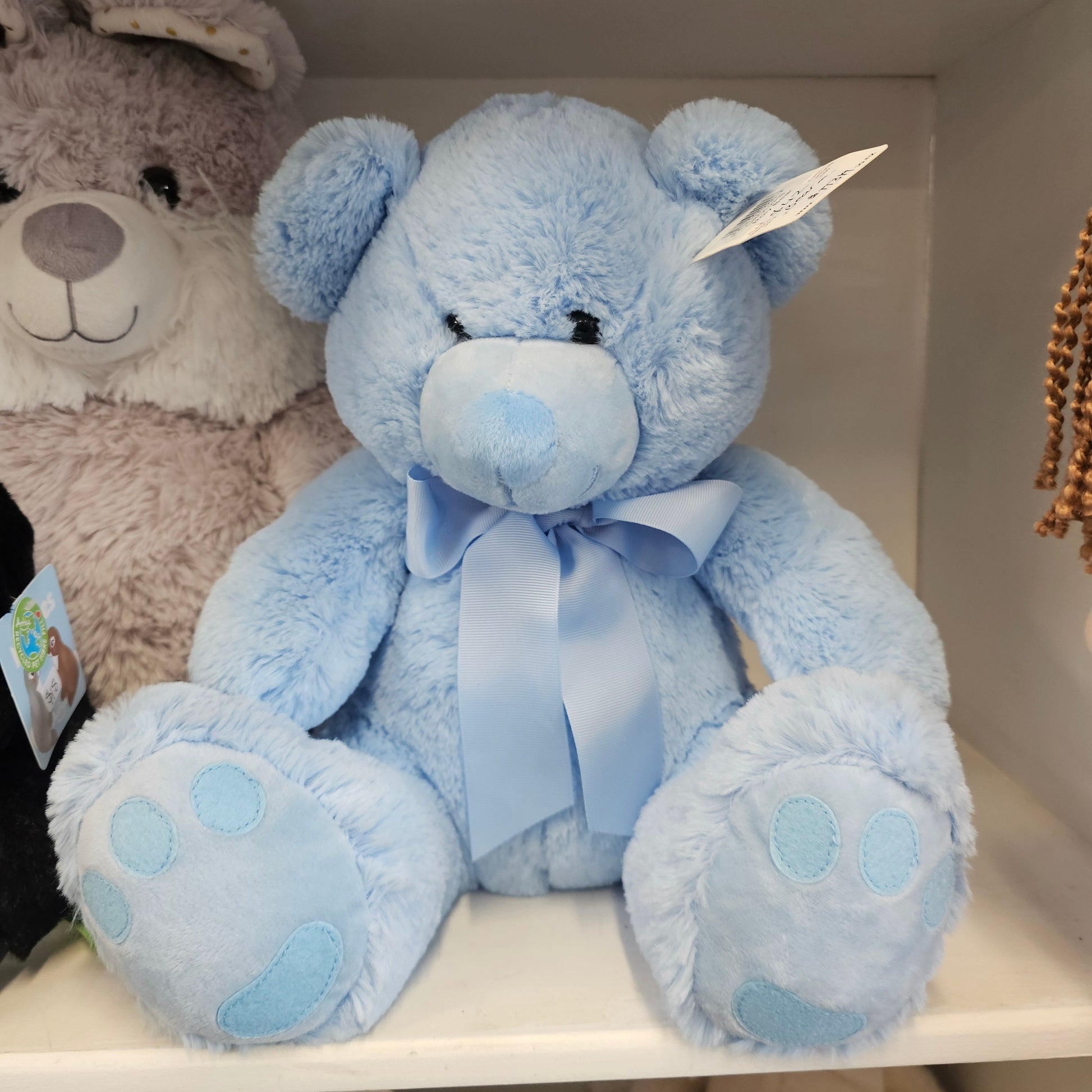 A light blue plush teddy bear with a matching blue satin bow and light blue paw pads
