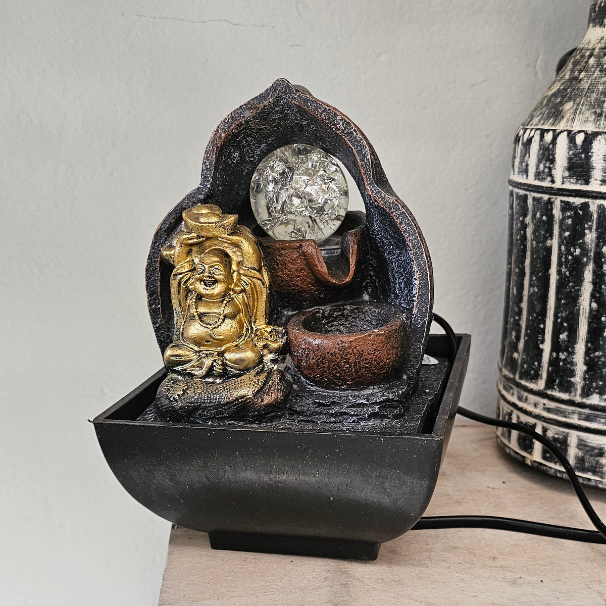 A small decorative tabletop fountain with a gold-toned Buddha figure.