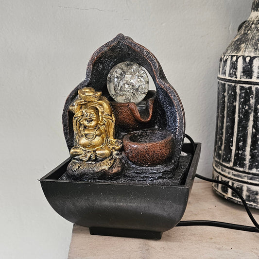 A small decorative tabletop fountain with a gold-toned Buddha figure.