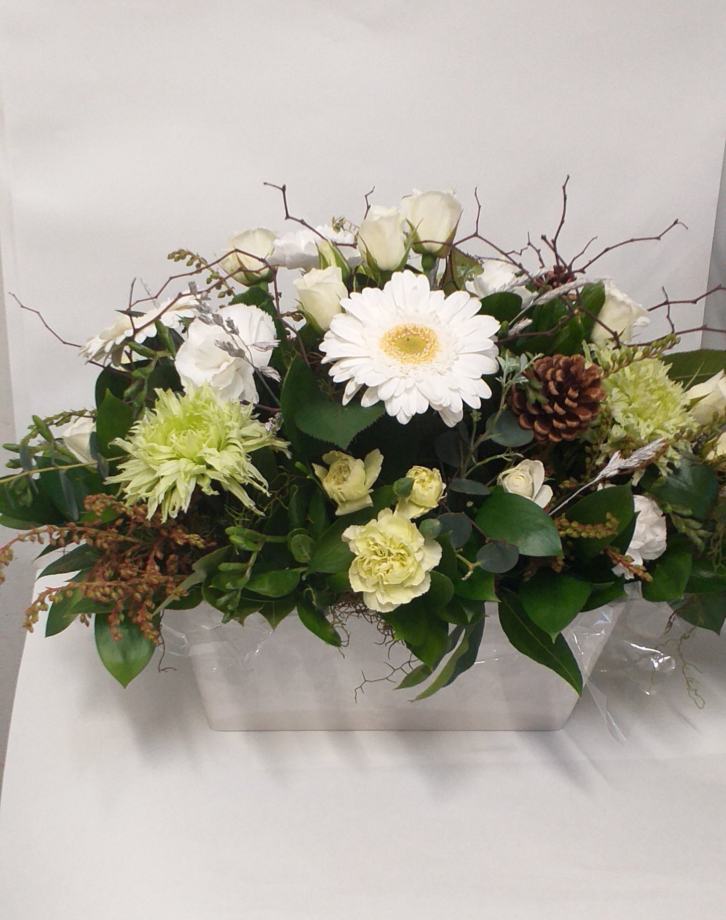 White mini roses, gerberas, green chrysies, spray carnation and cones