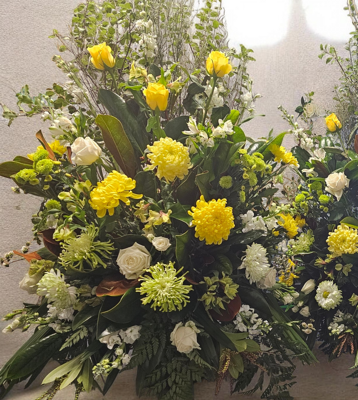 Floral arrangement with yellow and white flowers on a light background
