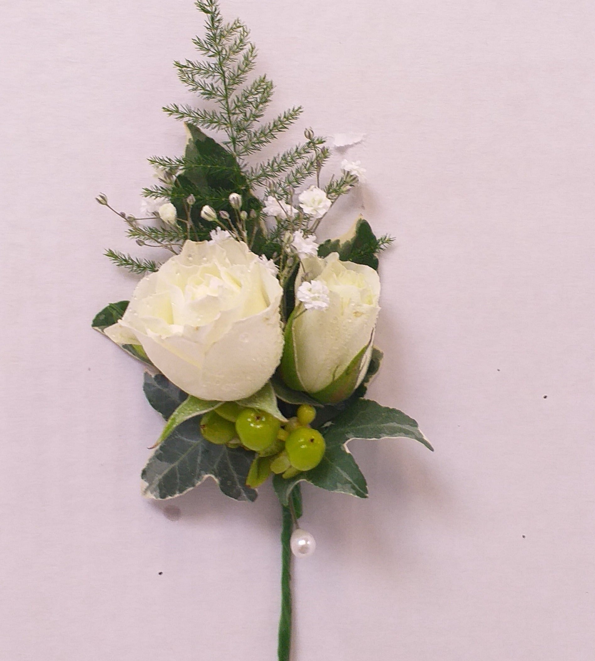 Lady's buttonhole or bouttoniere, white spray roses, hypericum berries, gypsophilla, fern and ivy leaves