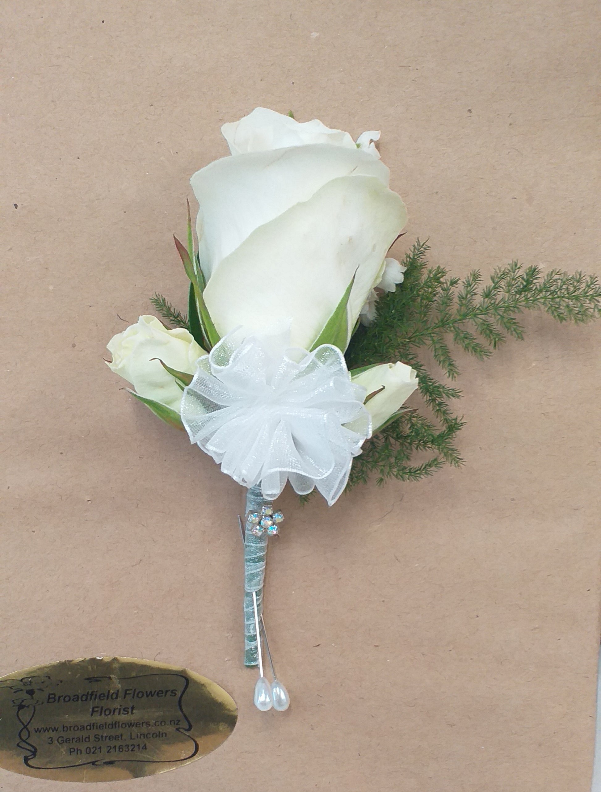 White rose buttonhole, with small additional decoration and ribbon