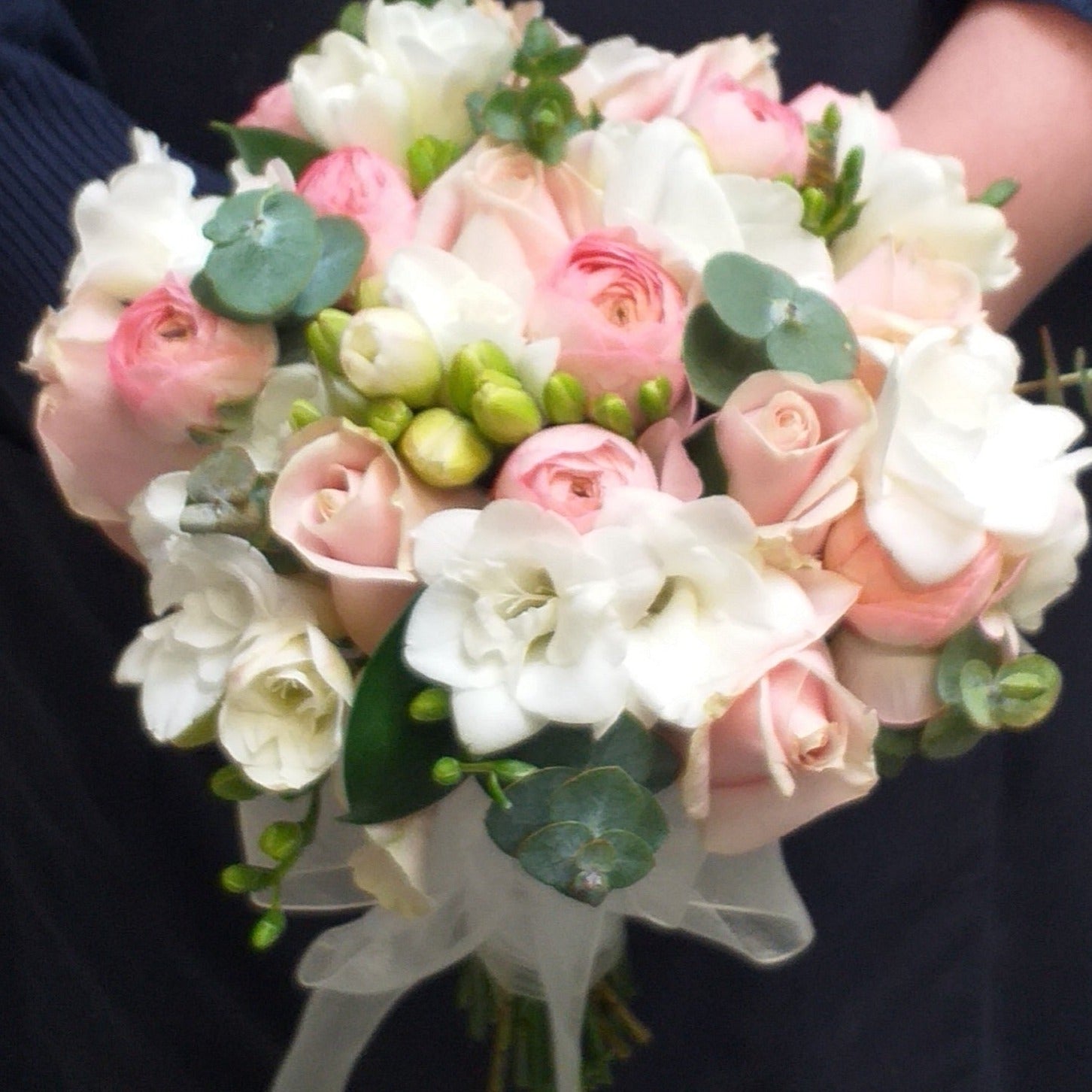 Bridal bouquet of white freesias, pink roses, pink ranunculus and baby blue gum