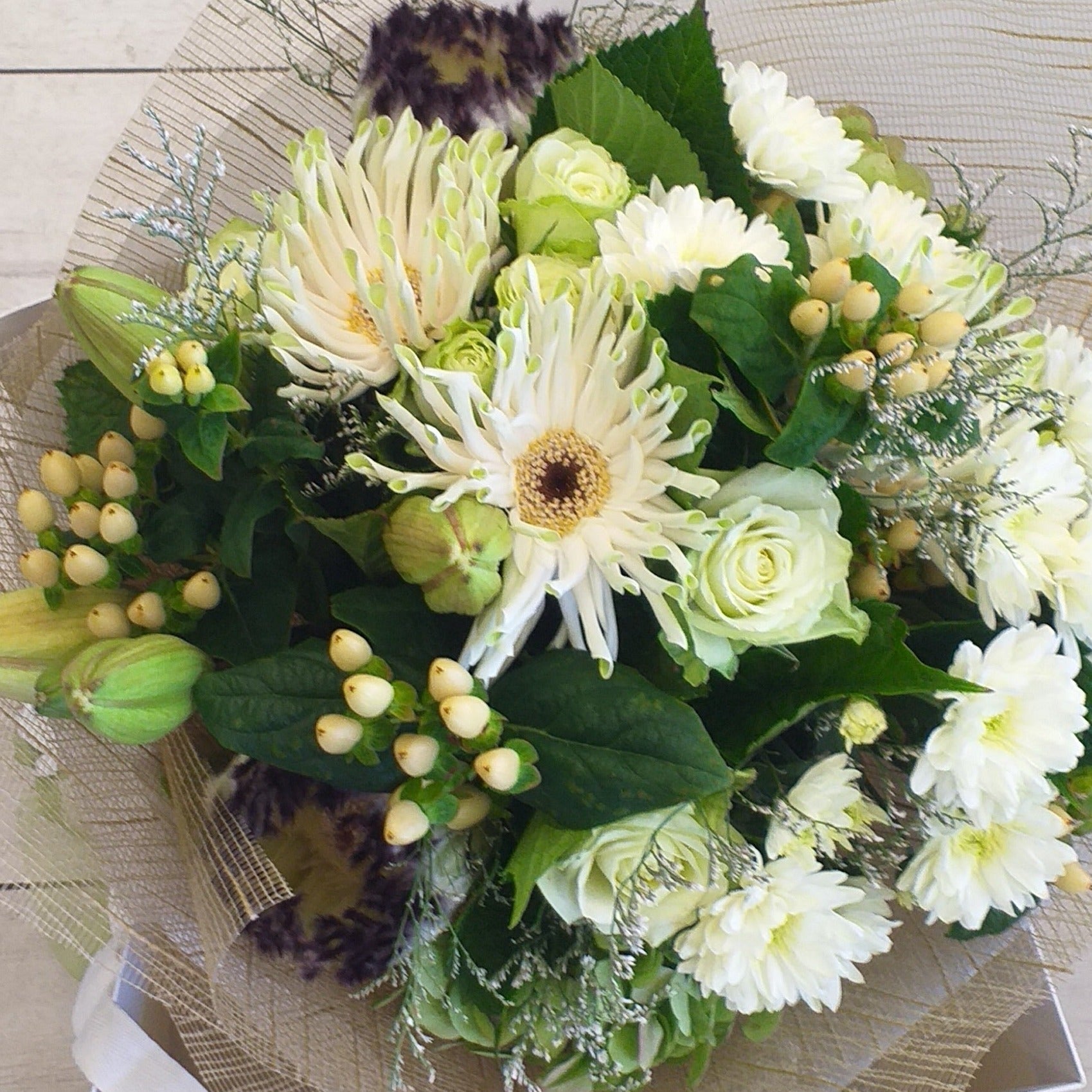 A beautiful bouquet of cream and green flowers including green roses, berries, protea, chrysies, lilies and gerberas.