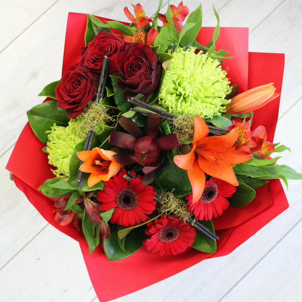 Heart Warmer flower bouquet, orange lily, green chrysanthemum, red leucadendron, gerberas, alstromeria wrapped in red