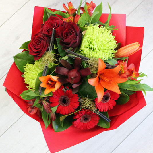 Heart Warmer flower bouquet, orange lily, green chrysanthemum, red leucadendron, gerberas, alstromeria wrapped in red