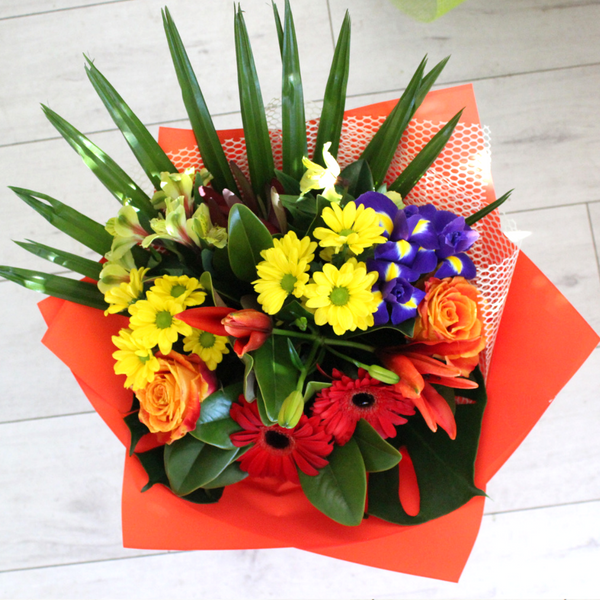 Bright and Bold bouquet, orange and pink roses, yellow chrysanthemums, blue and yellow iris, red gerberas, yellow alstroemeria, yellow palm, astatic lily. Wrapped in red and white.
