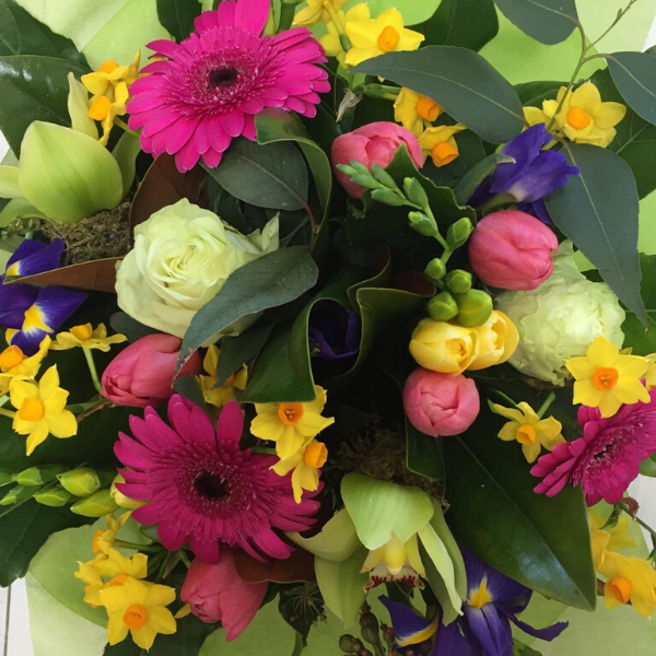 Candy flower bouquet, flowers included are pink gerberas, yellow freesias, white or cream roses, yellow and blue iris, pink tulips, green orchids, daffodils. Wrapped in lime green 