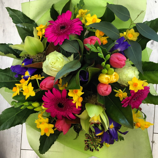 Candy flower bouquet, flowers included are pink gerberas, yellow freesias, white or cream roses, yellow and blue iris, pink tulips, green orchids, daffodils. Wrapped in lime green 