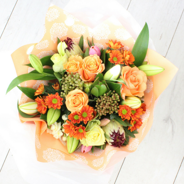 Apricot/peach coloured flowers, roses, protea, lilies, berries, chrysies