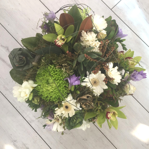 bouquet is made with interesting plant material to give a textured look. included are flax flowers, freesia, gerbera, pieris, orchids (when available), ice plant, molenbeckia, spray chrysies and moss